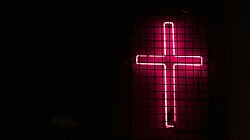 The Cross, signifying religion. Religions, which give dogmas that tend to keep people in subjugation, are among the creators of the woes of man. Spirituality must replace religionism.